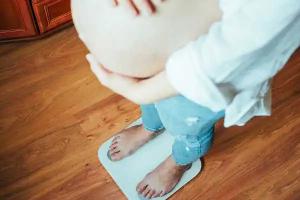 Image of woman weighing herself and experiencing weight gain through pregnancy Marlborough